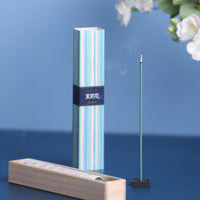 Incense stick with packaging and a wooden holder on a blue background